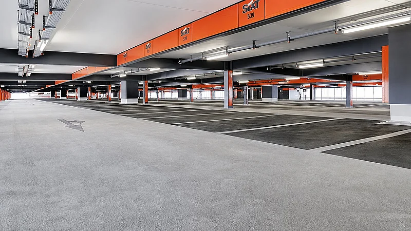 Beschichtete Parkhausfläche am Flughafen Berlin mit Fahrspur, Stellplätzen und orangefarbener Deckenmarkierung.