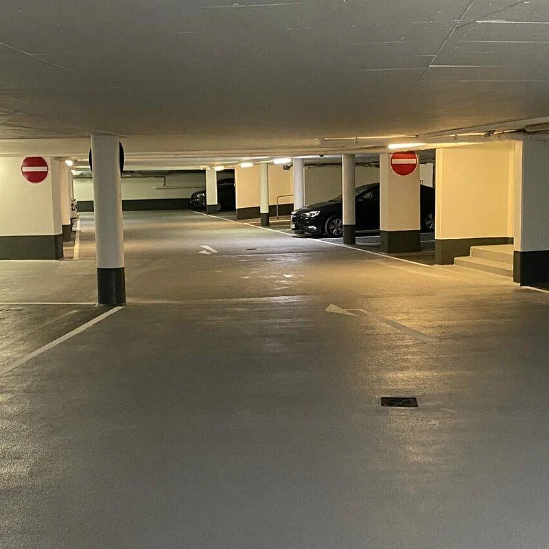 Fertig beschichtete Parkfläche in einer Tiefgarage mit Stützen, Fahrgasse und markierten Stellplätzen.