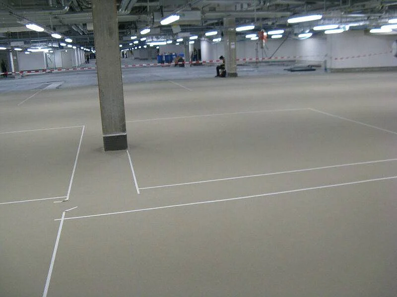 Fertig beschichtete Parkhausfläche mit markierten Stellplätzen und Betonstützen.